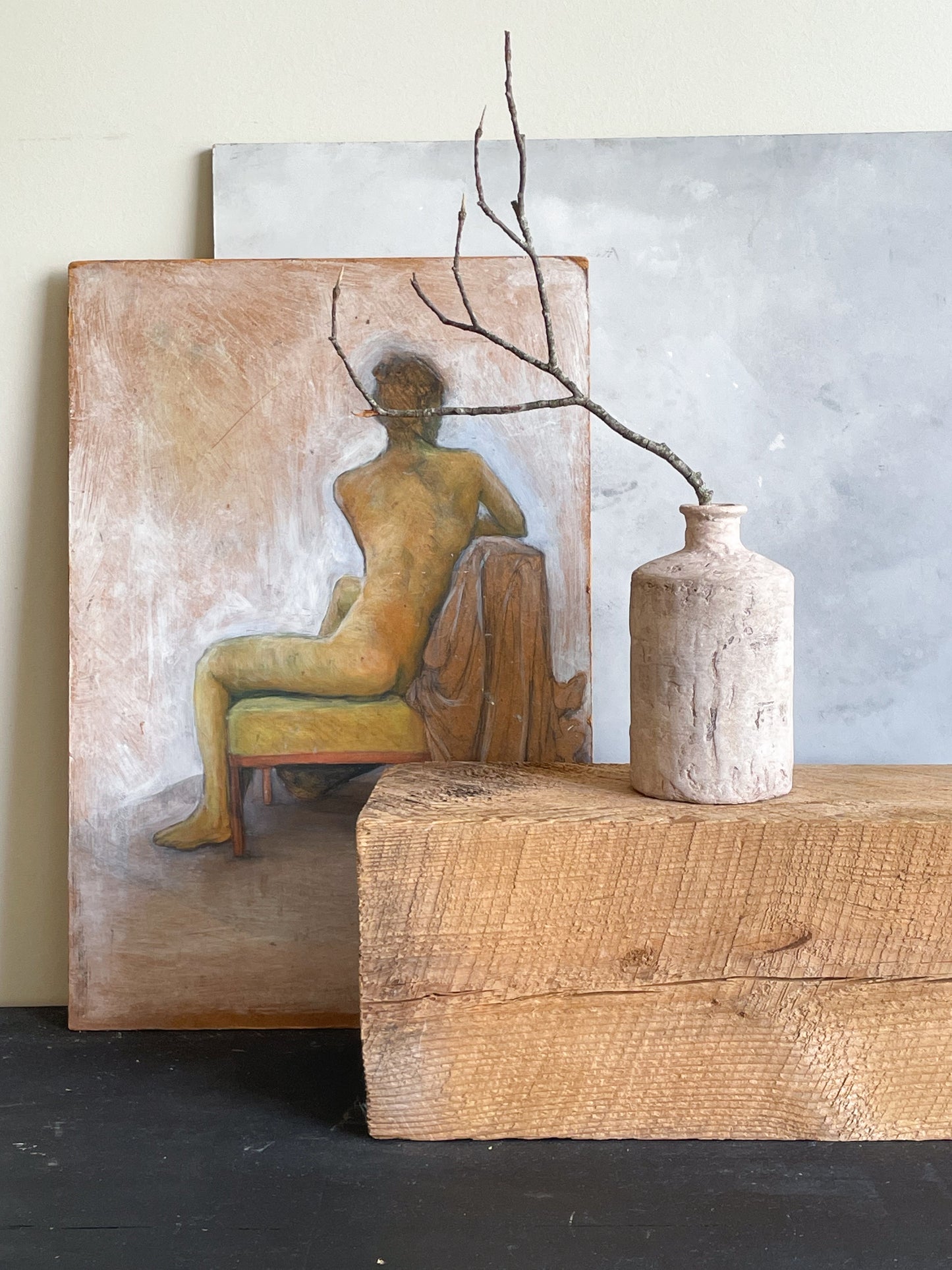 Rustic white textured vase holding dried branches on a tabletop.