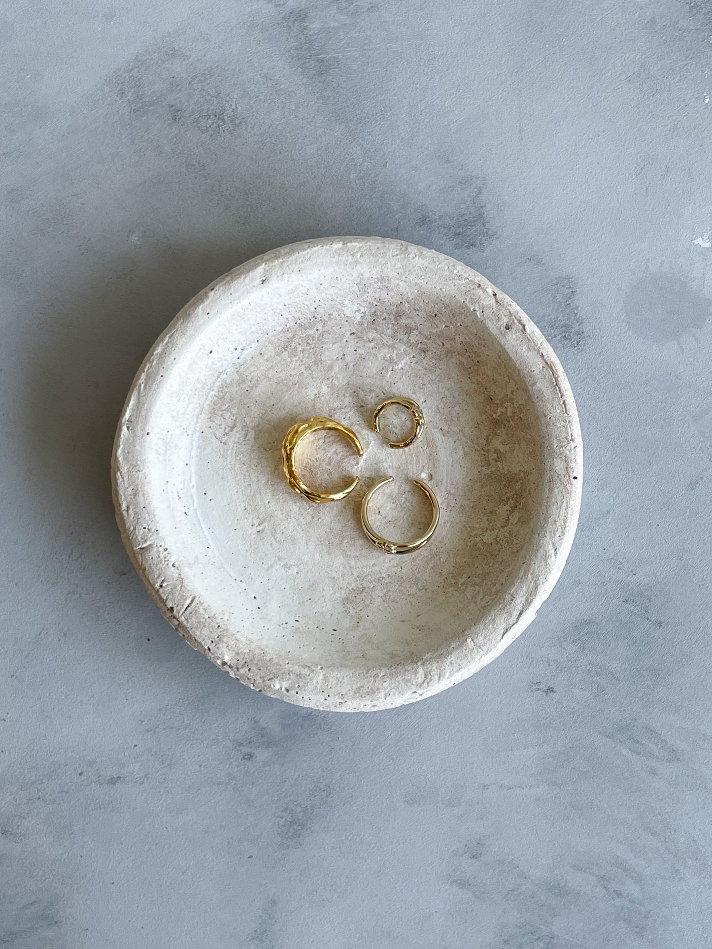 Top-down view of the handmade cement dish from the Milos Collection, featuring a smooth, rounded shape in light off-white tones.