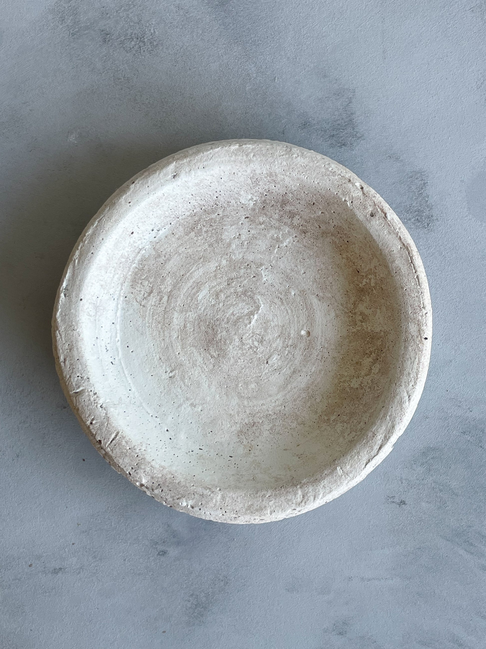 A beautifully crafted handmade cement dish from the Milos Collection, styled as a catchall for small items, with a textured finish in light, neutral tones.