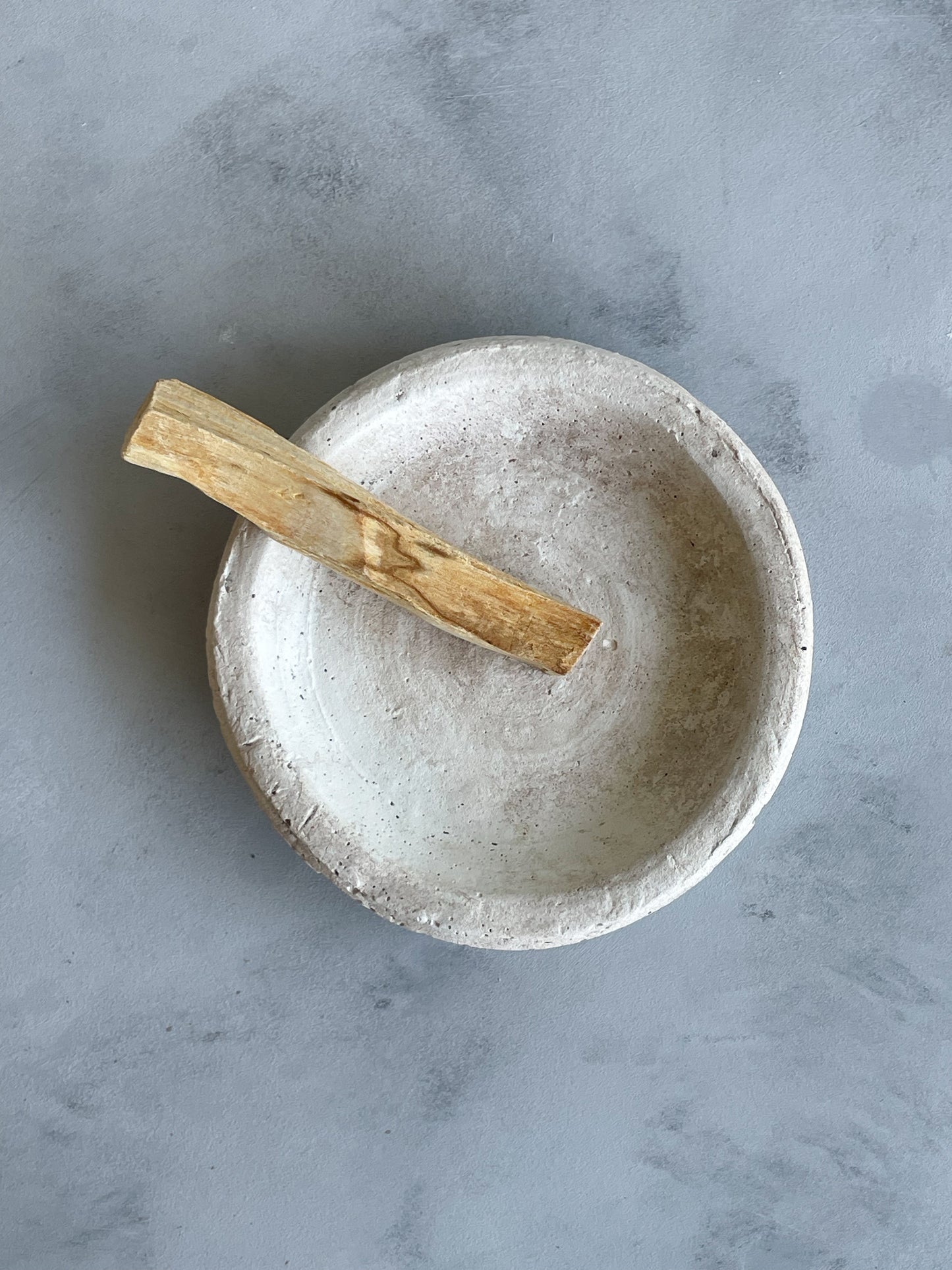 Detail of the textured cement finish on the decorative dish from the Milos Collection, in neutral off-white and beige tones.