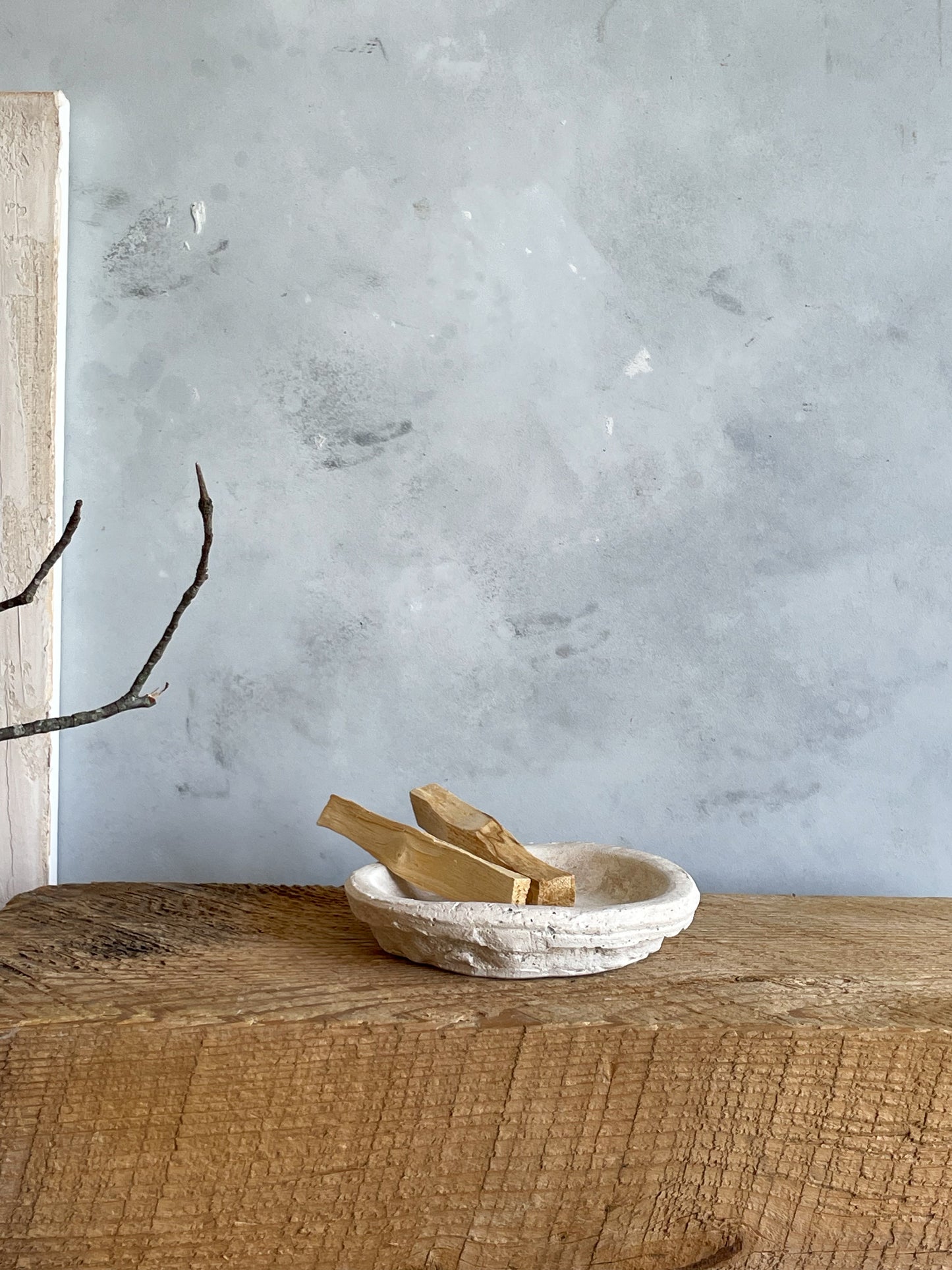 The Milos Collection handmade cement dish, photographed on a natural wood surface, emphasizing its rustic, minimalist charm.