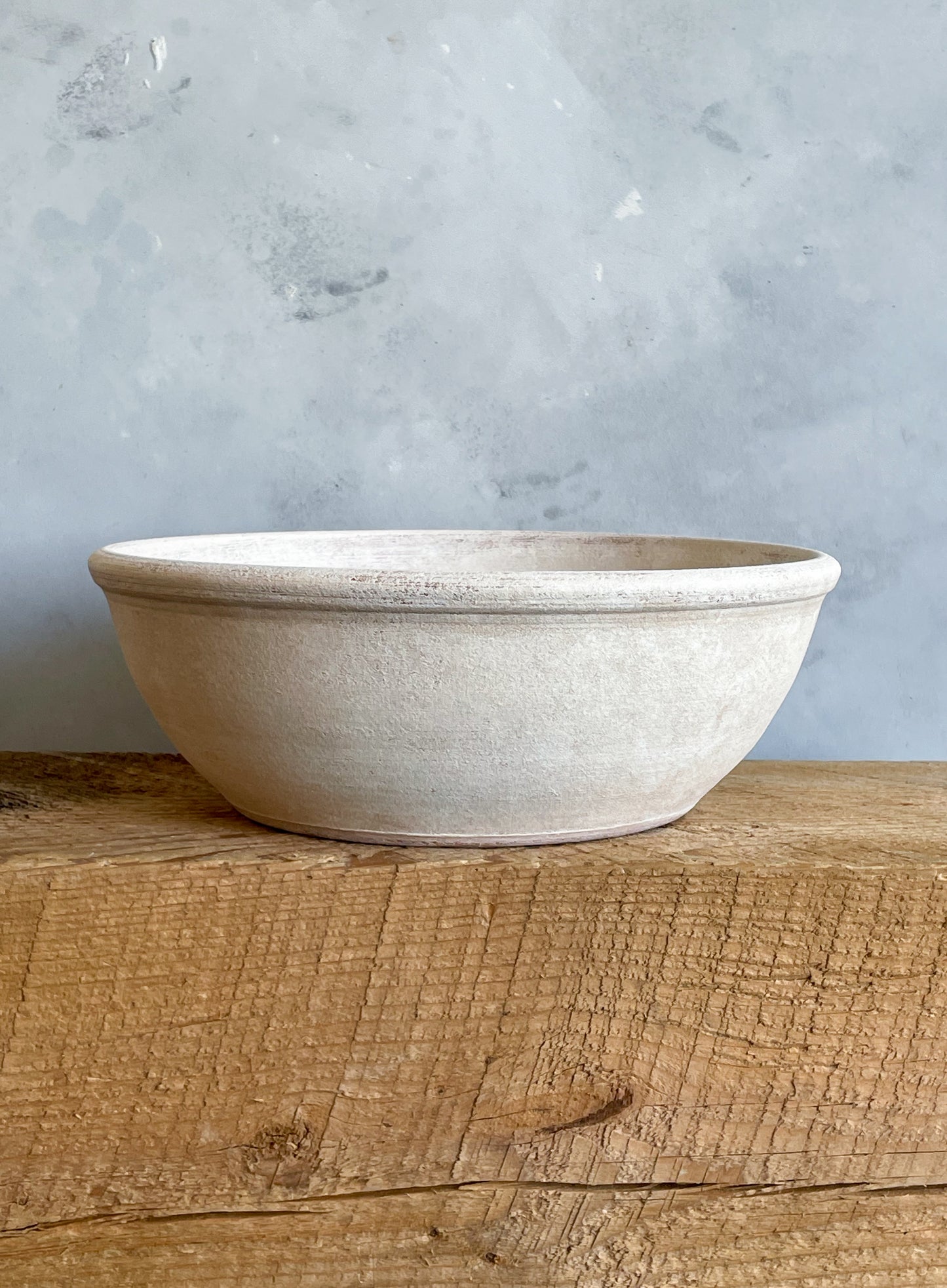 Side view of the aged white ceramic bowl, highlighting its rustic charm.