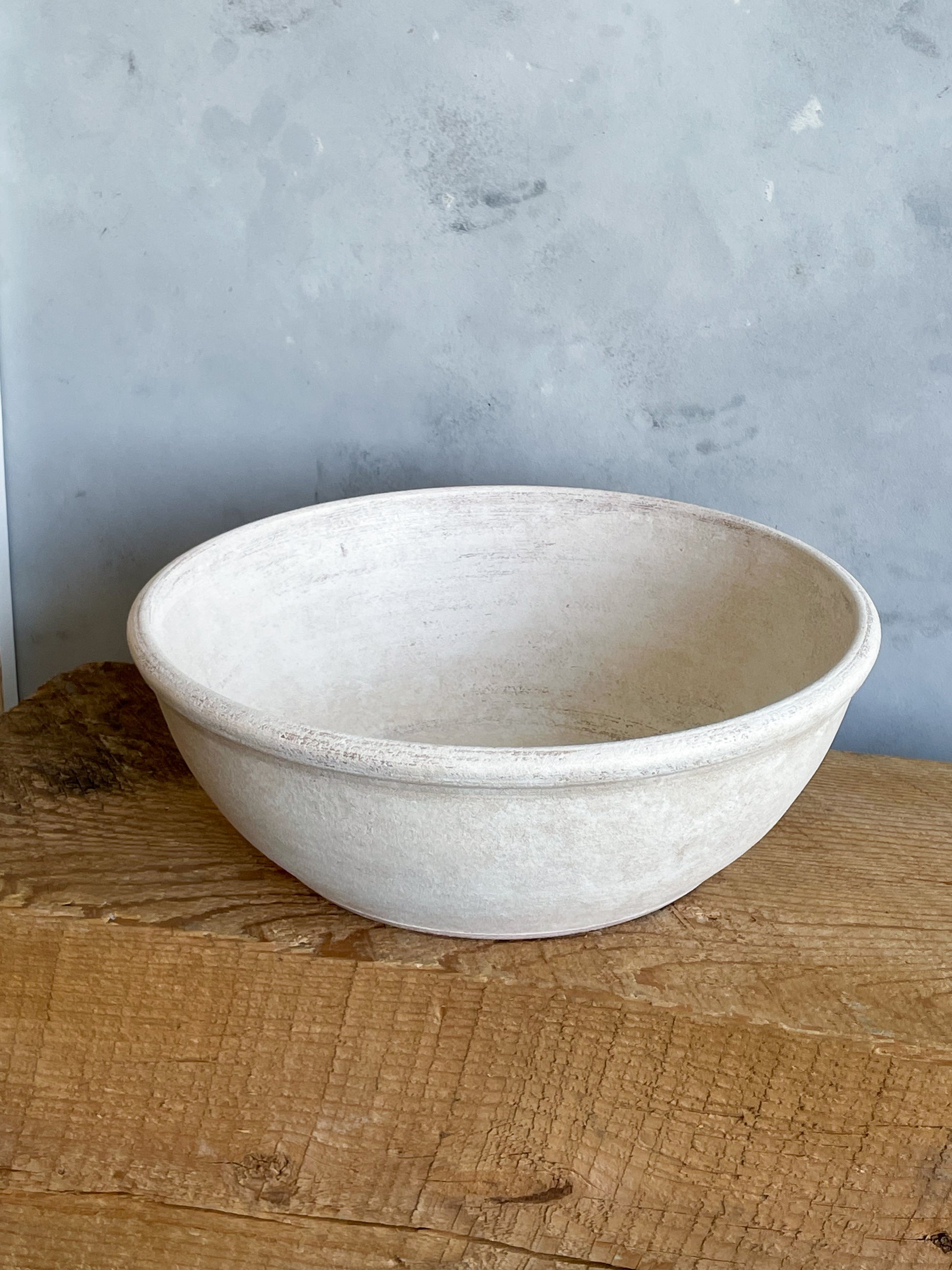 Side view of the aged white ceramic bowl, highlighting its rustic charm.